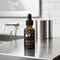 Moonshine Mike's Skunk Ape Beard Oil bottle on a kitchen countertop with modern decor.