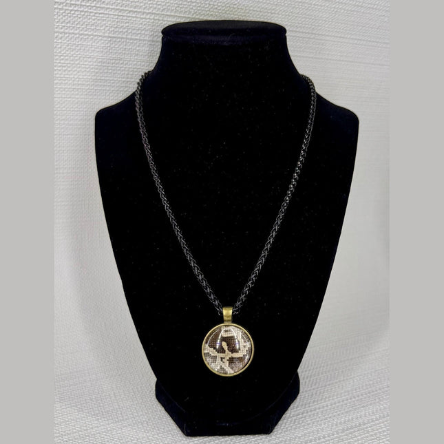 Fort Denaud Beard and Skin round pendant necklace with a textured pattern in a bronze frame on a black braided cord