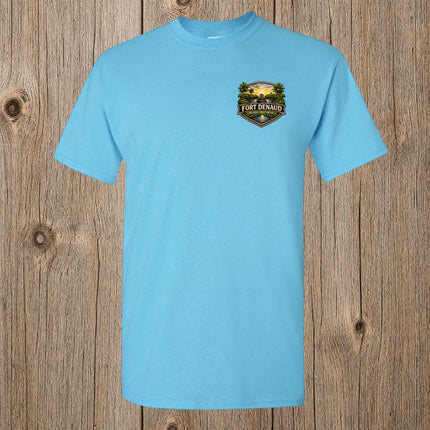 Fort Denaud Beard and Skin sky blue cotton t-shirt with a detailed chest badge graphic on a rustic wood background.