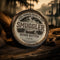 Fort Denaud Beard and Skin Smuggler unscented beard butter in a 2 oz metal tin on a rustic wooden dock.